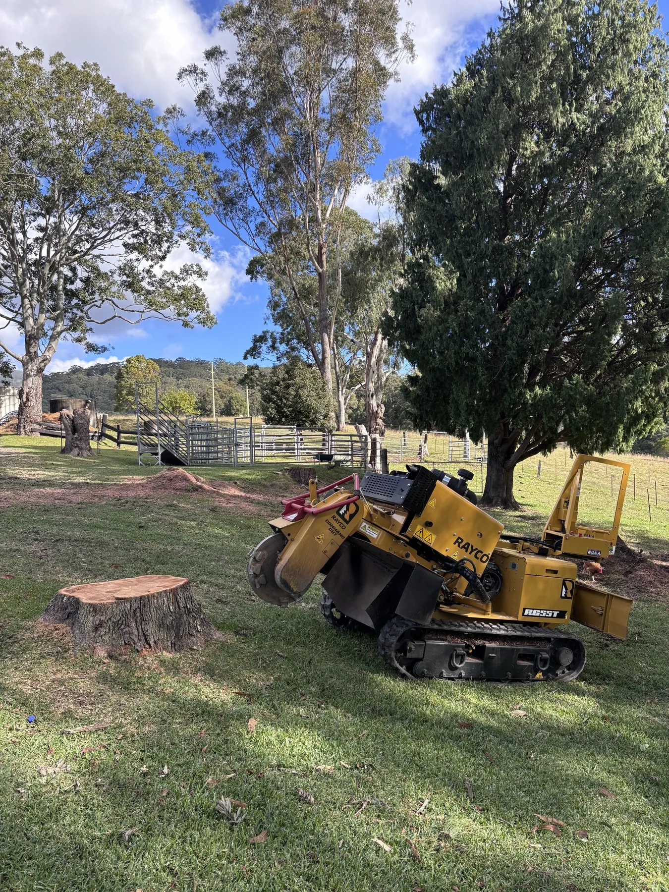 Stump grinder parked beside a freshly ground stump on a rural property
